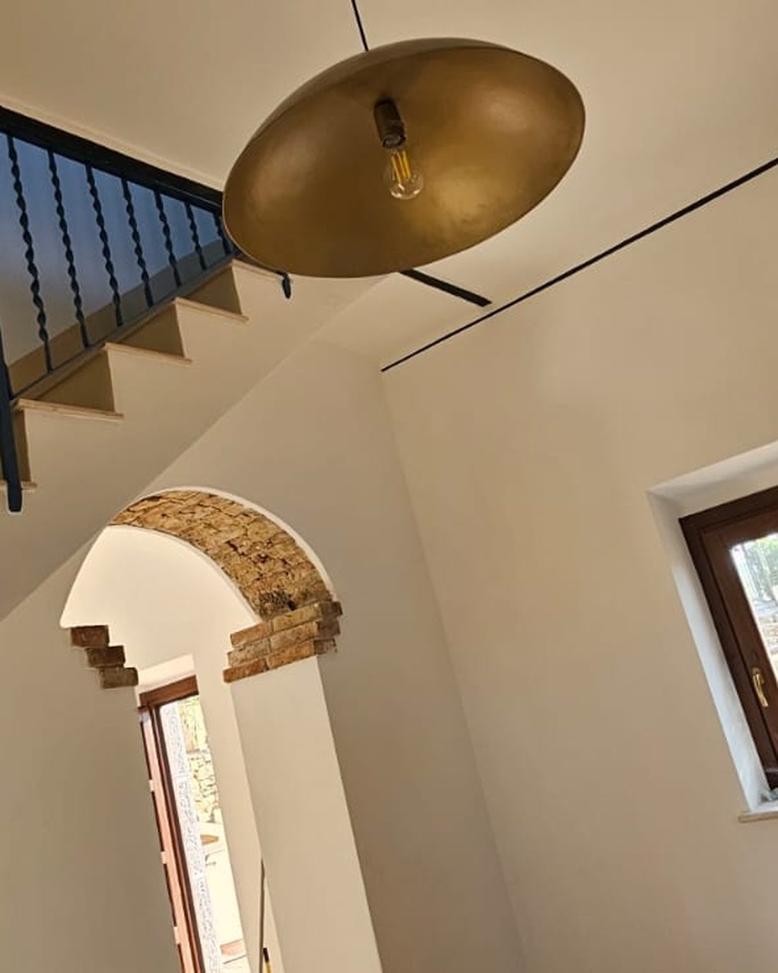 Ambiente interno del casello con alte pareti a calce, arco in mattoni e luce dalle finestre in legno