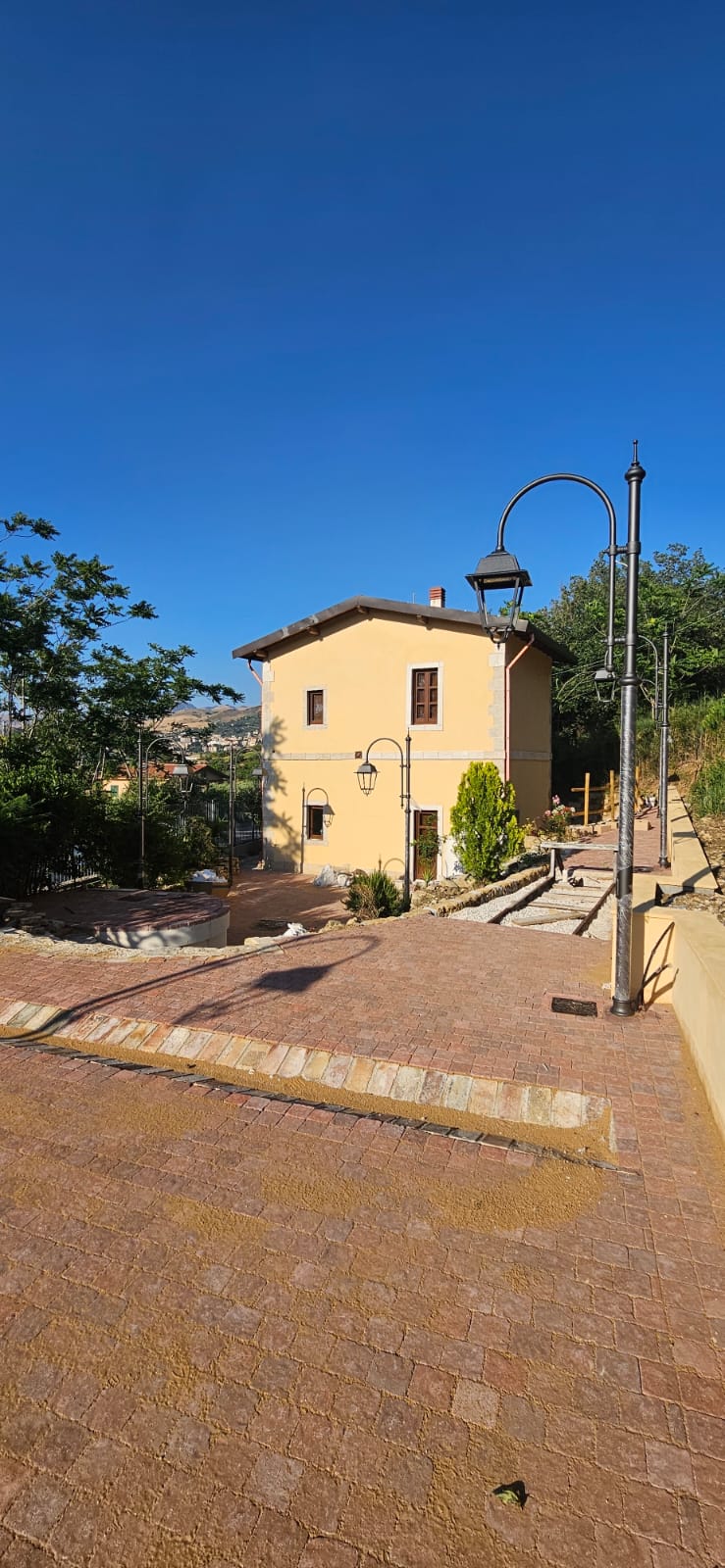 Il casello visto dalla corte selciata, con la fila di lampioni e Corleone sullo sfondo