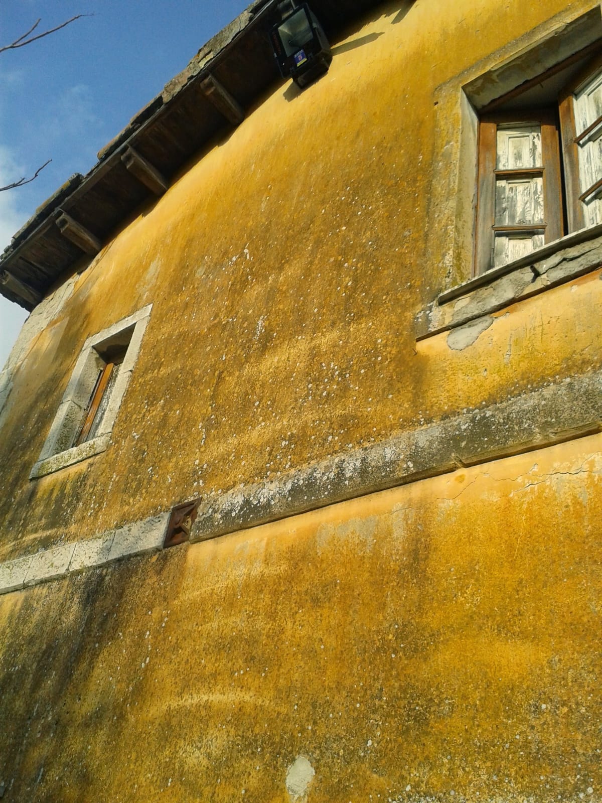 La facciata del casello prima del restauro: intonaco a calce ocra dilavato, conci di pietra calcarea attorno alle aperture e infissi in legno deteriorati