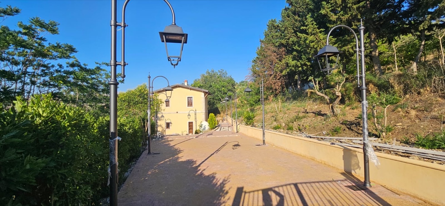Il vialetto alberato con i lampioni che conduce al casello, pronto ad accogliere i visitatori